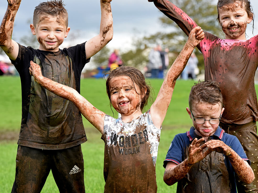 Four children covered in mud after run